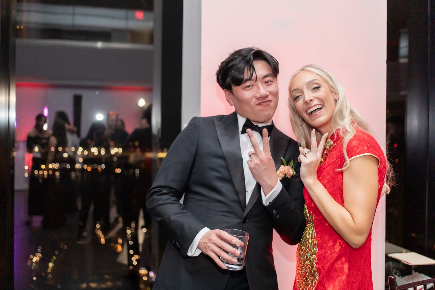   The bride and groom give the camera the peace sign after the bride changed into her red Qipao during her State Room Boston wedding reception