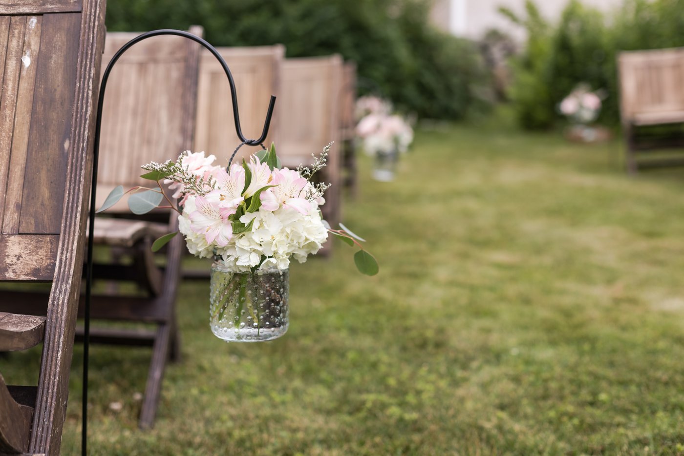 Mason jars hang on hooks that line the aisle at an outdoor rustic wedding at a barn in Massachusetts