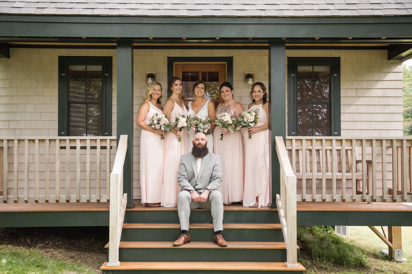 The bride and her bridal party standing by a small cabin at a barn wedding MA