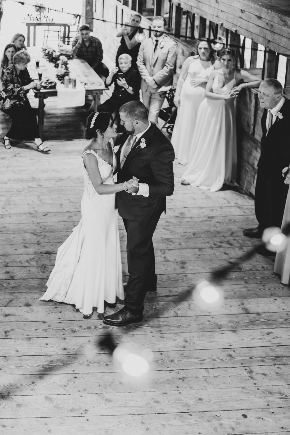 A black and white photo of the bride and groom dancing in the barn during their first dance at a barn wedding in Massachusetts