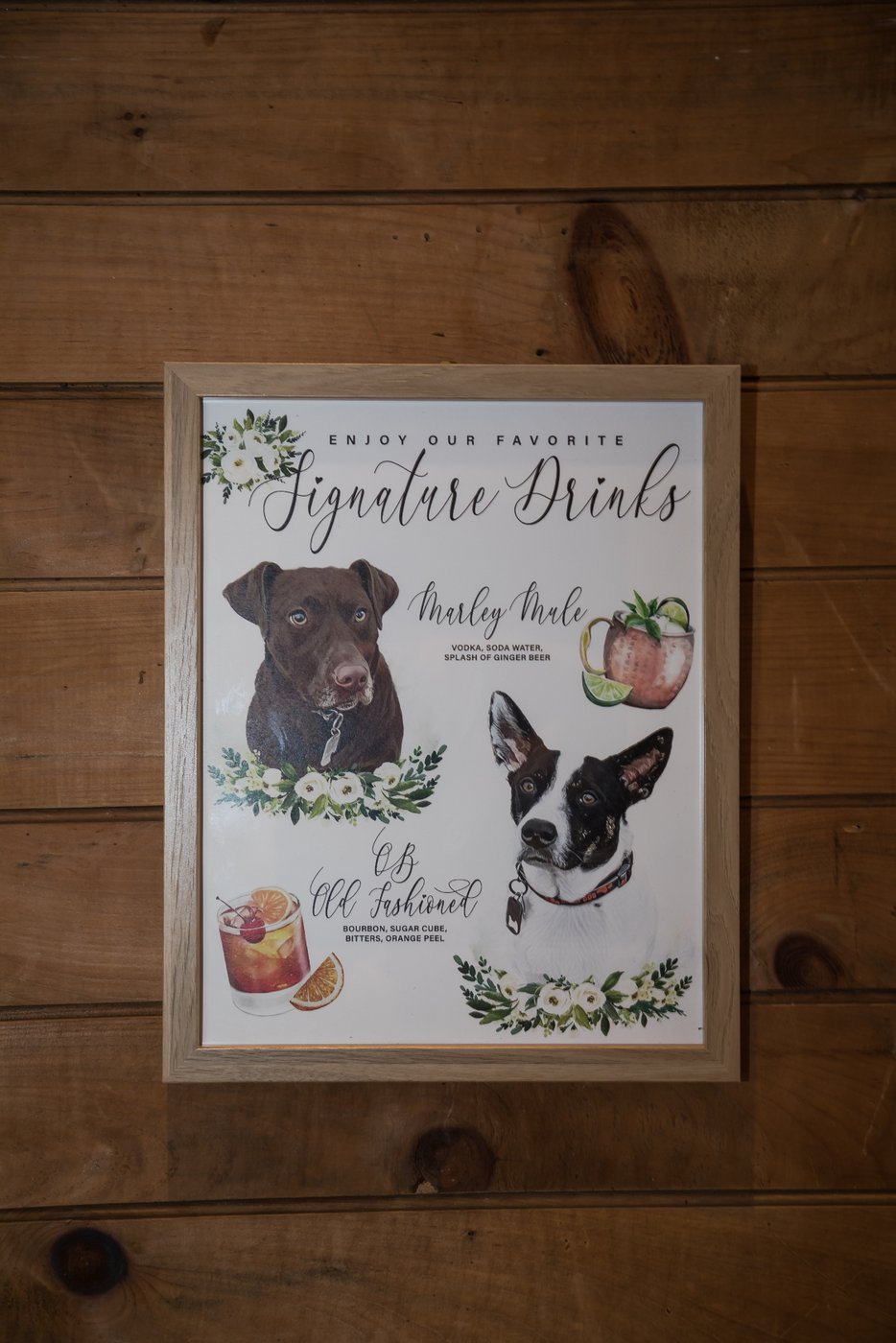 A framed sign of the couple's signature drink options, featuring illustrations of their dogs, at a barn wedding in Massachusetts