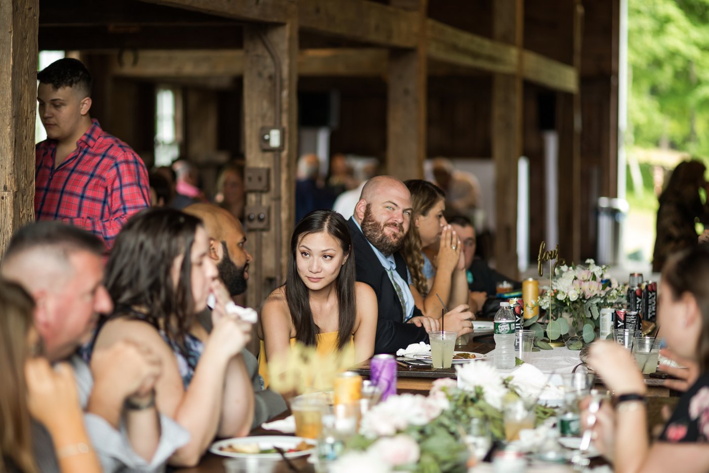Guests sitting at long wooden tables at a rustic wedding in Massachusetts