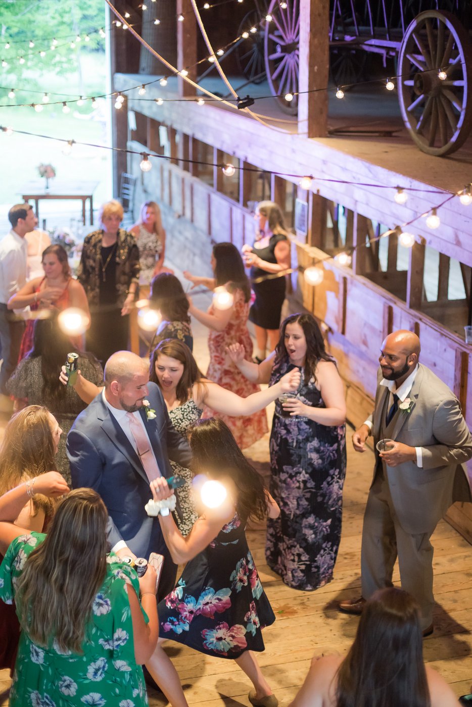 Guests dancing, shot from above through string lights at a rustic wedding in a barn in Massachusetts