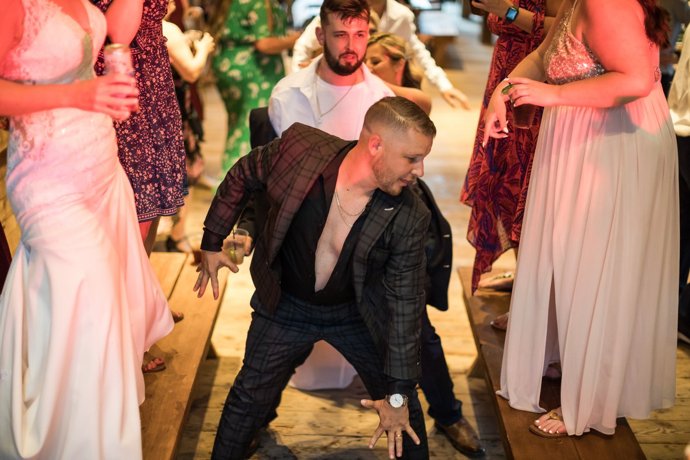 Guests dancing under string lights at a rustic wedding in a barn in Massachusetts
