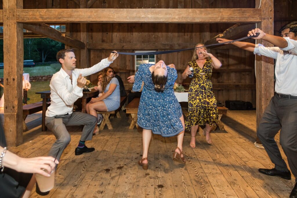 Guests doing the limbo in a barn at a rustic wedding in Massachusetts