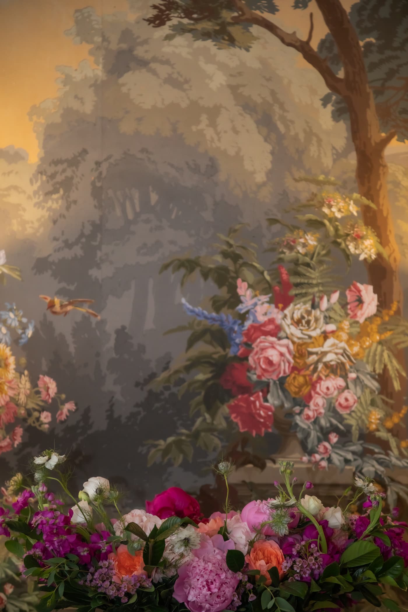 A wedding floral arrangement positioned in front of a renaissance painting at the King's Chapel Parish House in Boston, captured by artistic wedding photographers Spagnolo Photography.