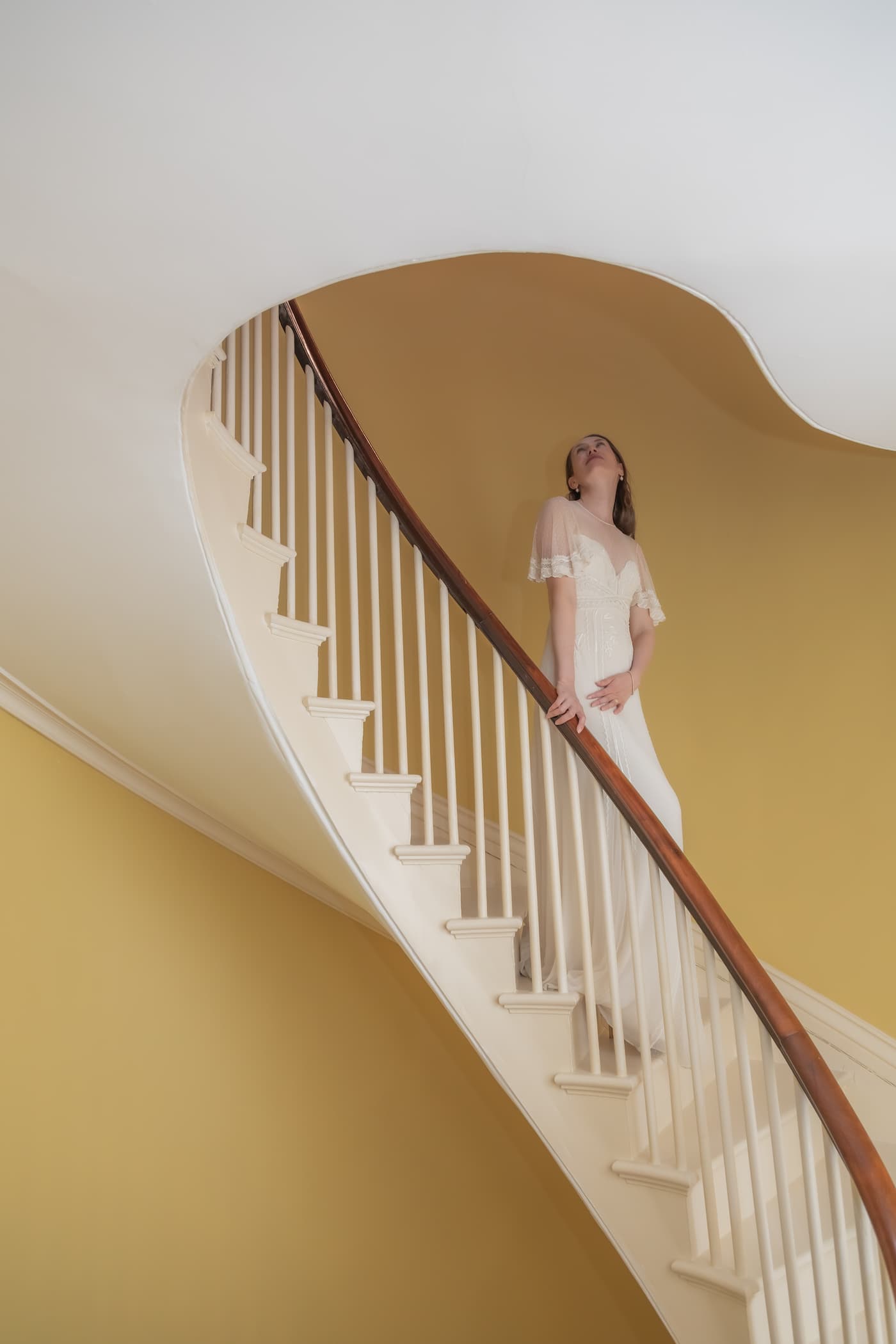 A creative portrait of a Boston bride descending the stairs at the Kings Chapel Parish House on her wedding day, photographed by Boston wedding, micro wedding, and elopement photographers Spagnolo Photography.