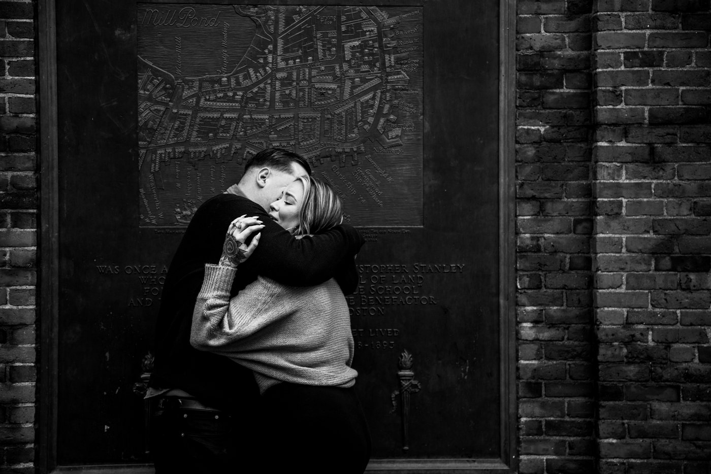 A black and white image of a couple hugging in a doorway in Boston, photographed during their Boston engagement photoshoot