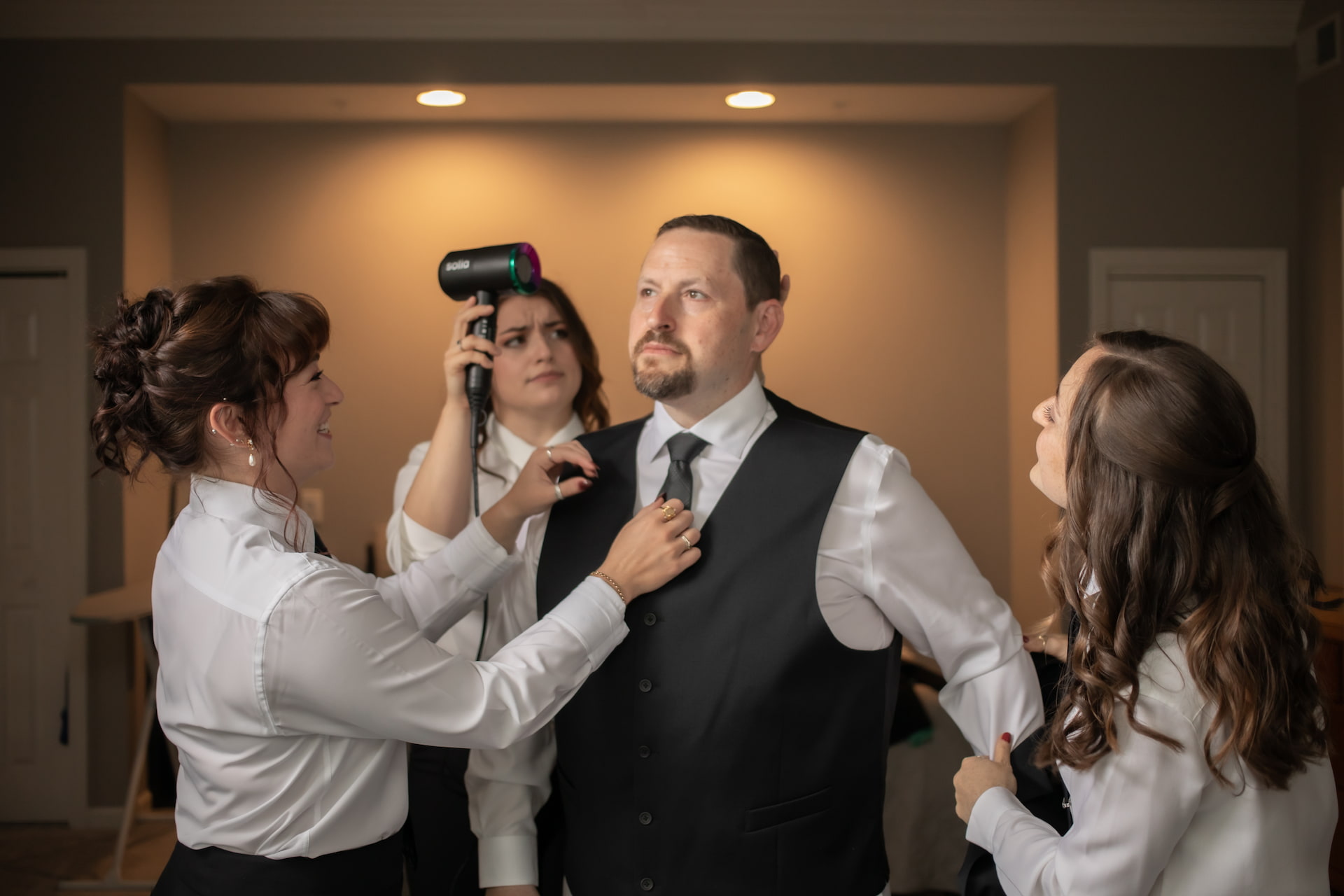 A groom getting ready for his wedding with the help of his three adult daughters, photographed in a candid and cinematic style by Boston wedding photographers Spagnolo Photography.