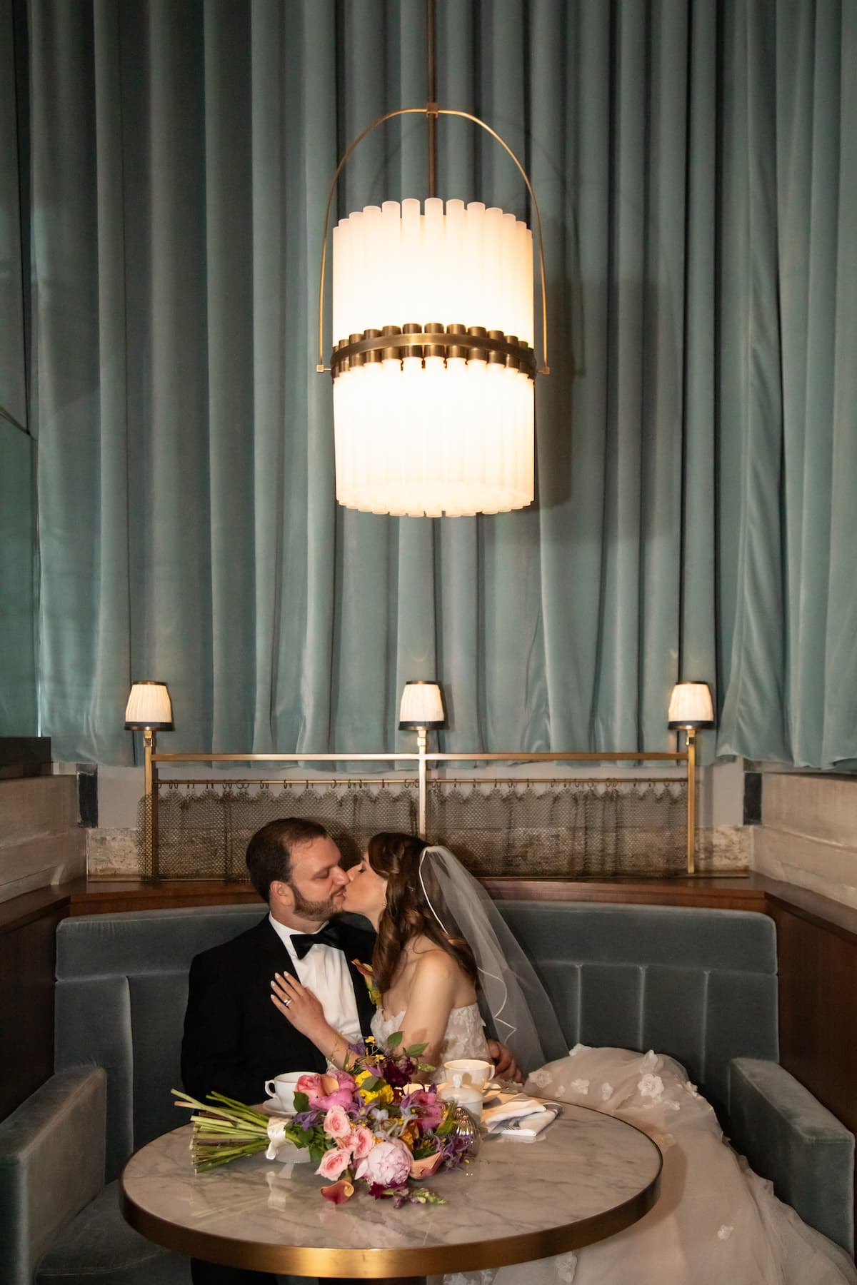 A bride and a groom cozy up in a lush velvet booth at Grana Restaurant during their Langham Boston wedding, photographed by creative wedding photographers Spagnolo Photography