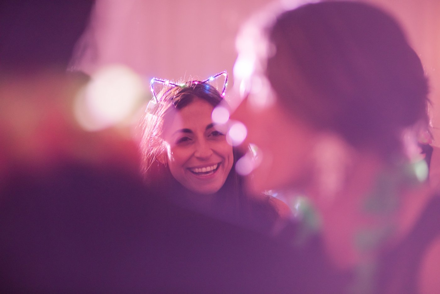 A wedding guest wearing glow-in-the-dark cat ears smiles during the Hora Loca dance party in a tented Misselwood Estate wedding reception, photographed in a candid style by Boston's Spagnolo Photography.
