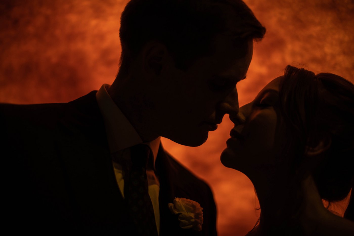 A dramatic portrait of a bride and a groom leaning close for a kiss in front of a model of the sun during their Museum of Science Boston wedding, photographed by creative Boston wedding photographers Spagnolo Photography.
