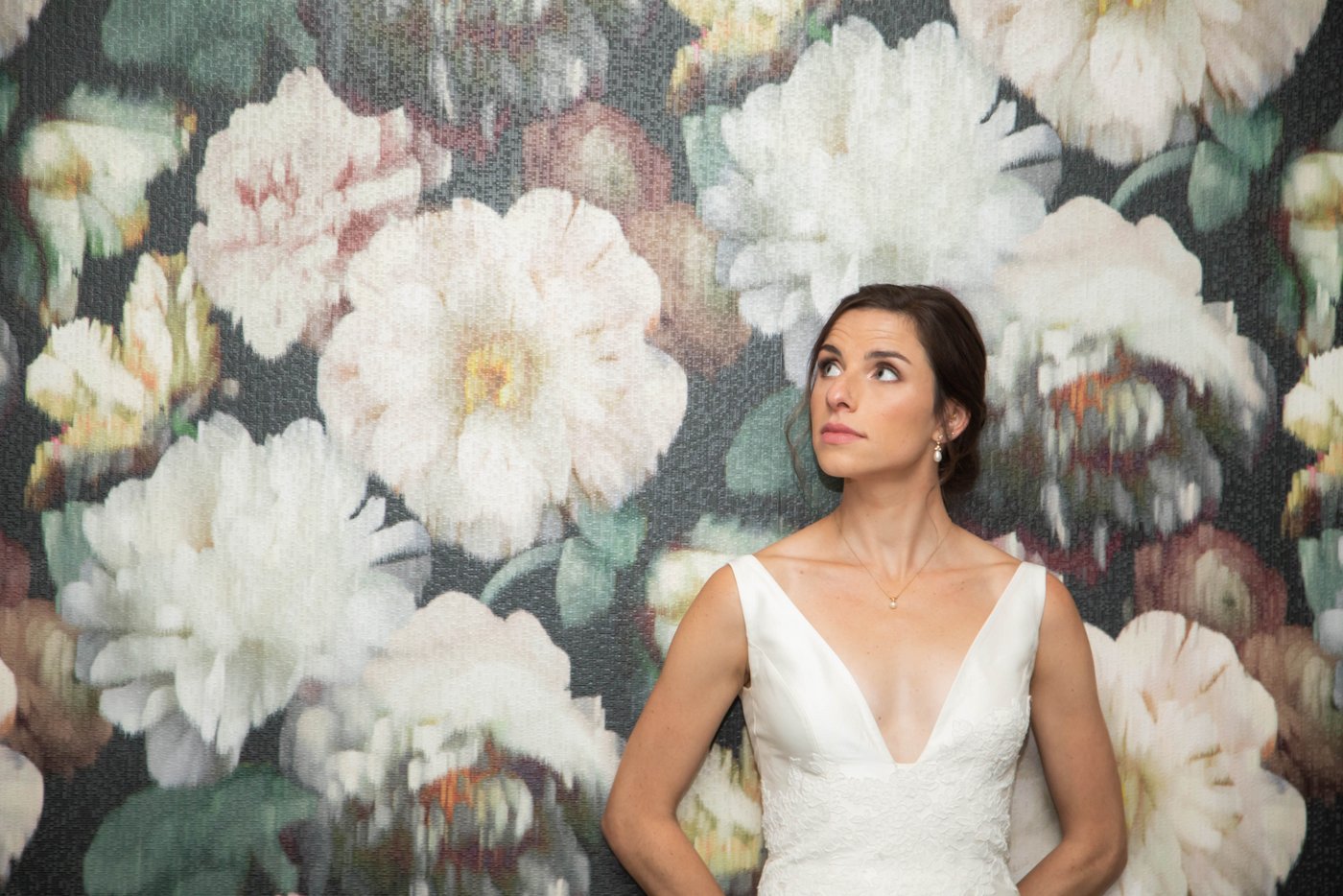 Bride standing against floral wallpaper before her fall wedding in Brookline.