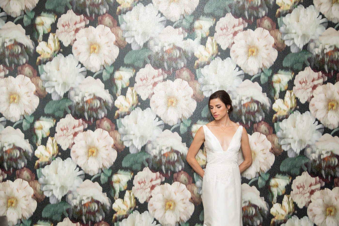 Bride leaning against awll covered with floral wallpaper before her fall wedding in Brookline.