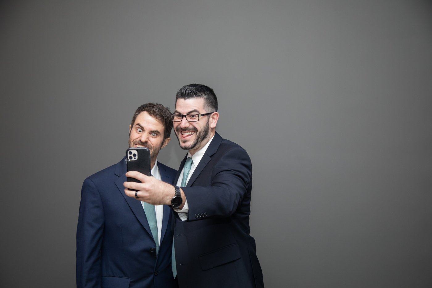 A candid shot of groomsmen taking a goofy selfie at fall wedding in Brookline.