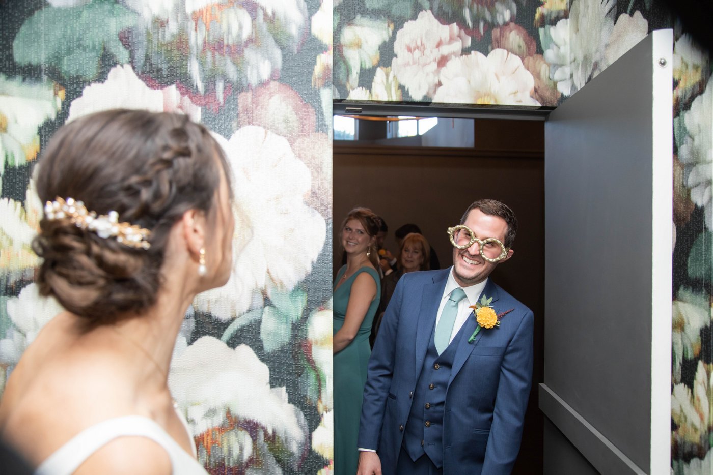 The groom entering the bride's room while wearing giant goofy bronze glasses