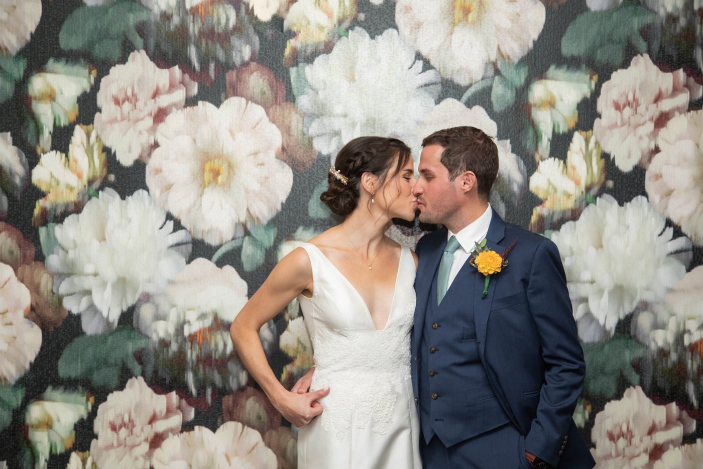 Bride and groom kissing while standing against a floral wallpaper before their fall wedding in Brookline, MA, photographed in a natural candid style by creative Boston wedding photographers Spagnolo Photography