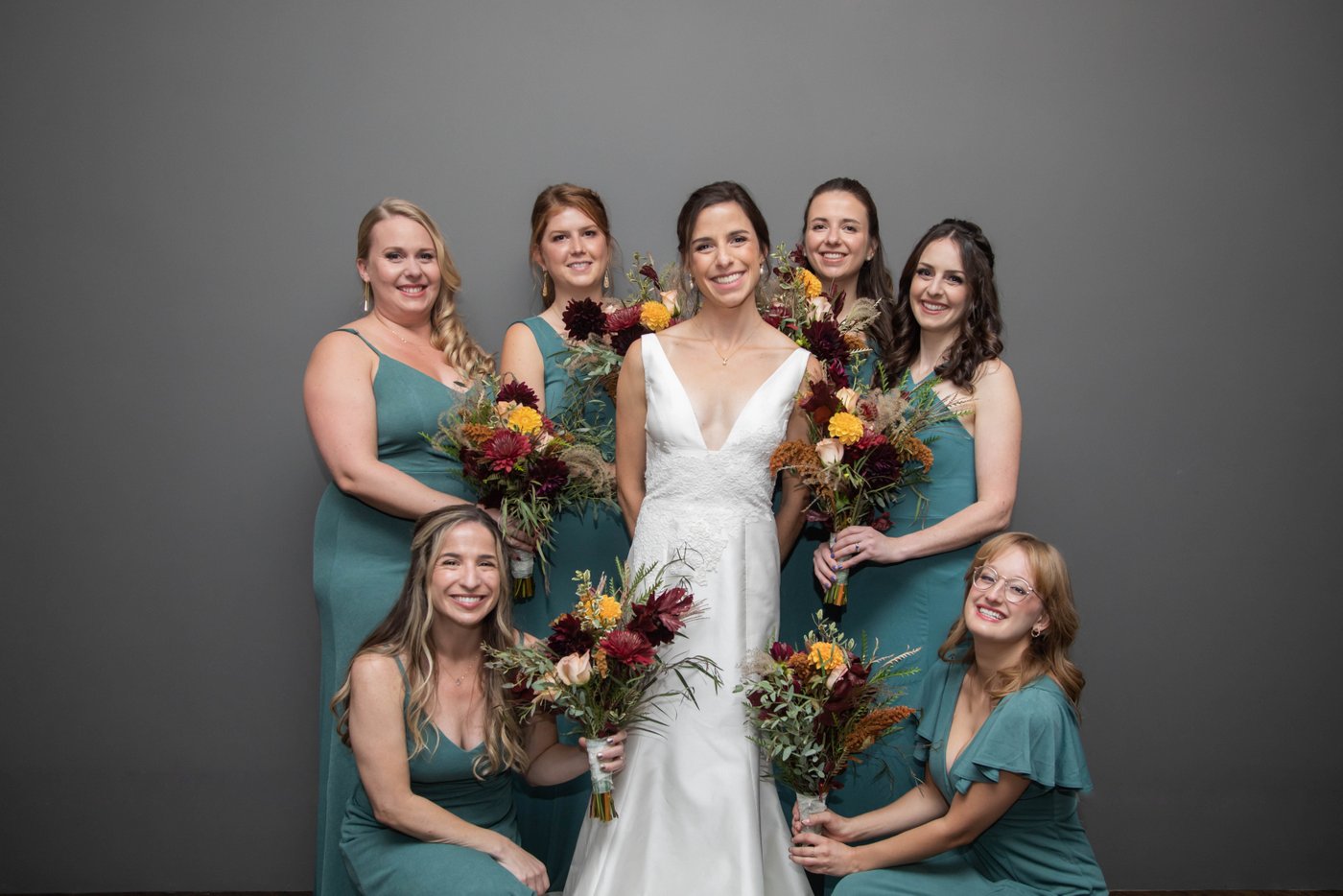A portrait of a bride and her bridesmaids posing against a gray wall at a Jewish wedding in Brookline, MA