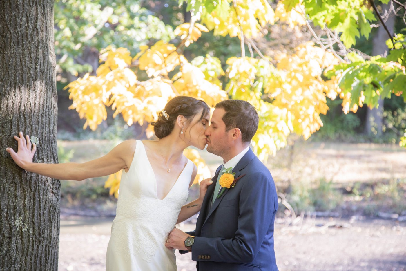 Bride and groom kiss at the Riverway Park in Brookline during their wedding portraits at their fall wedding in Brookline.