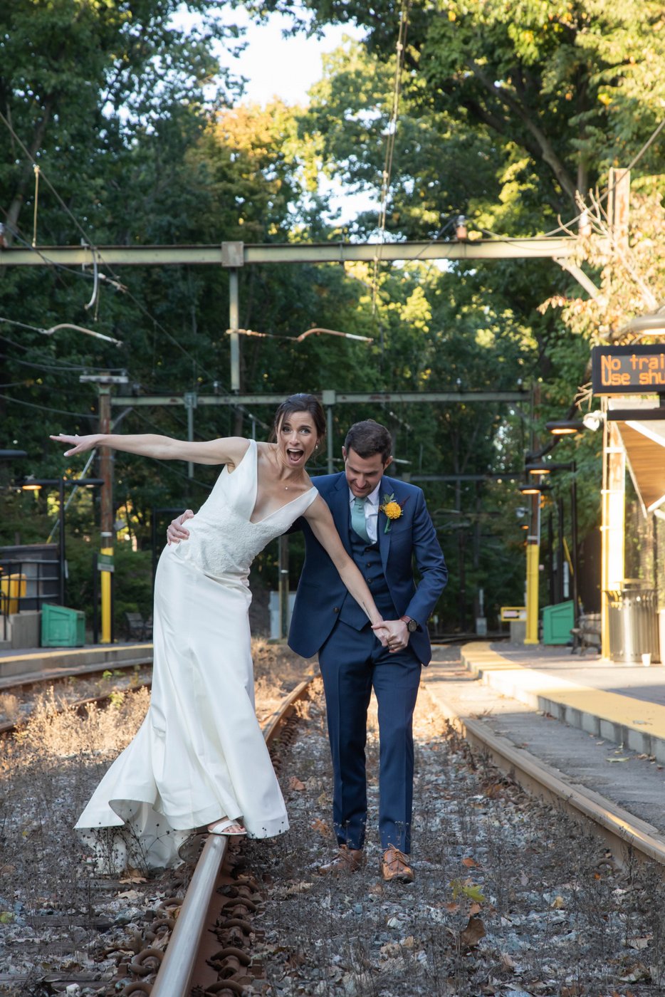 Bride and groom on train tracks near the Riverway Park in Brookline, MA, before their fall wedding celebrations