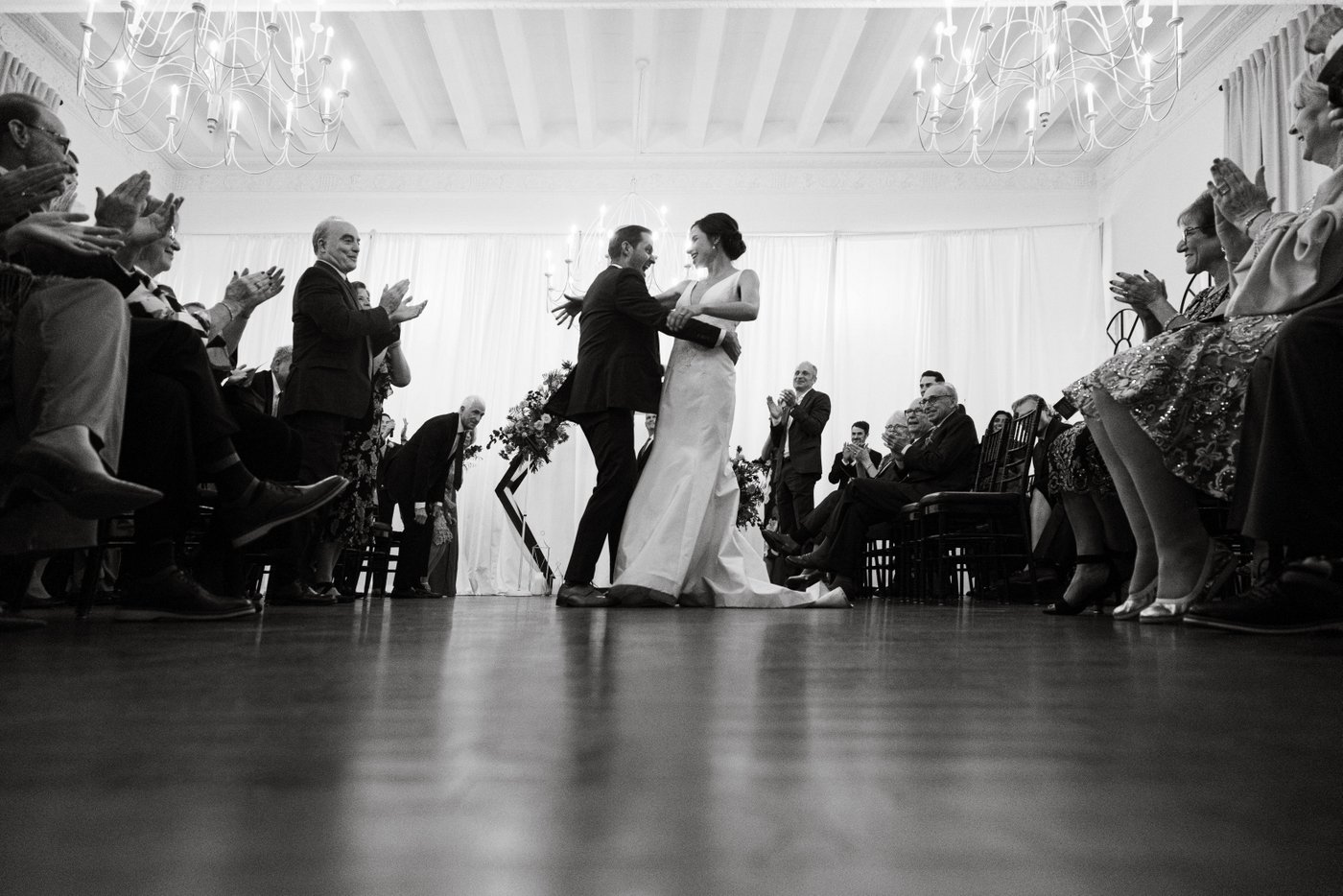 The groom dips the bride during their exit at their fall Jewish wedding in Brookline MA, photographed in black and white by Spagnolo Photography