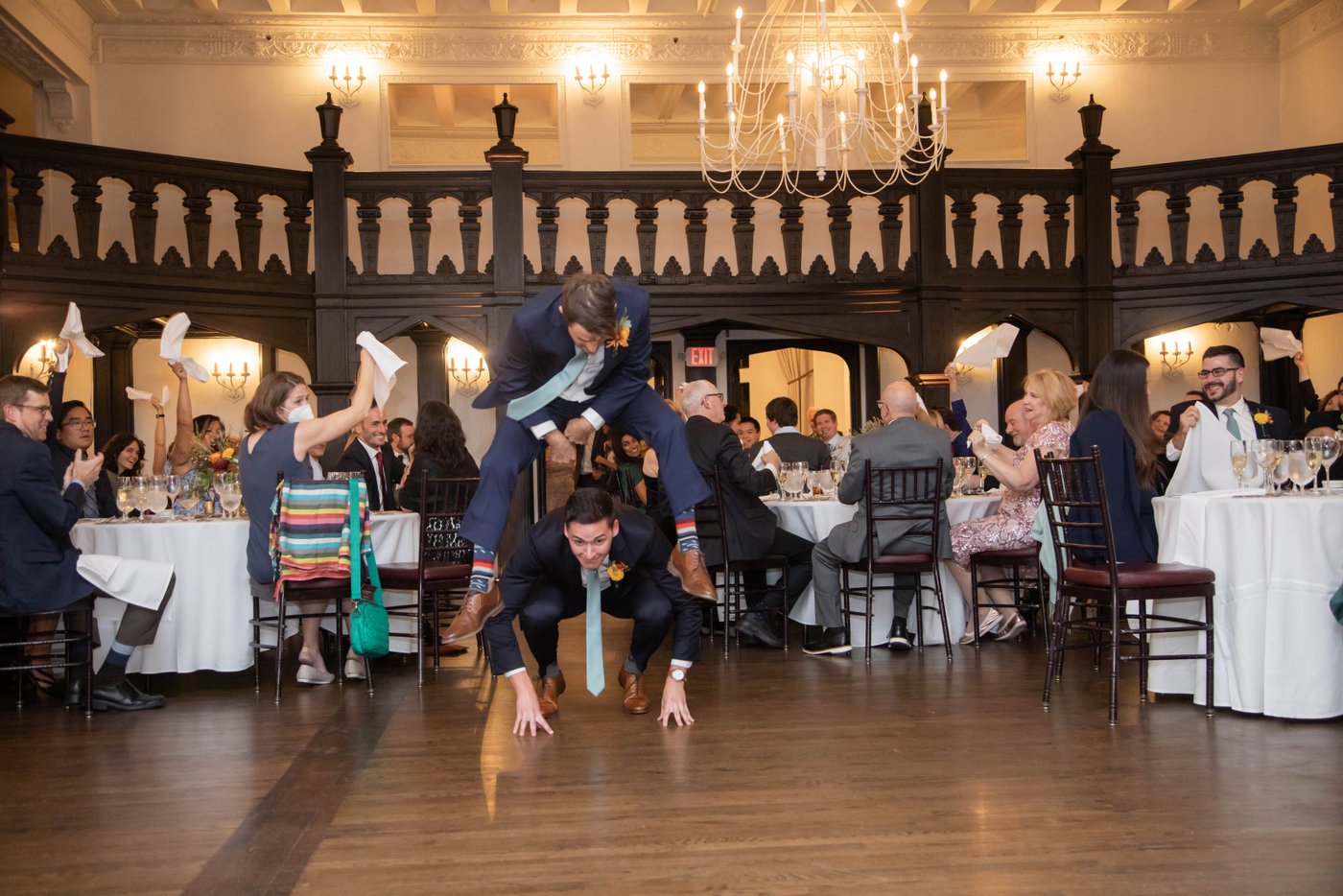 Bridal party entrance features groomsmen jumping over each other at fall wedding in Brookline