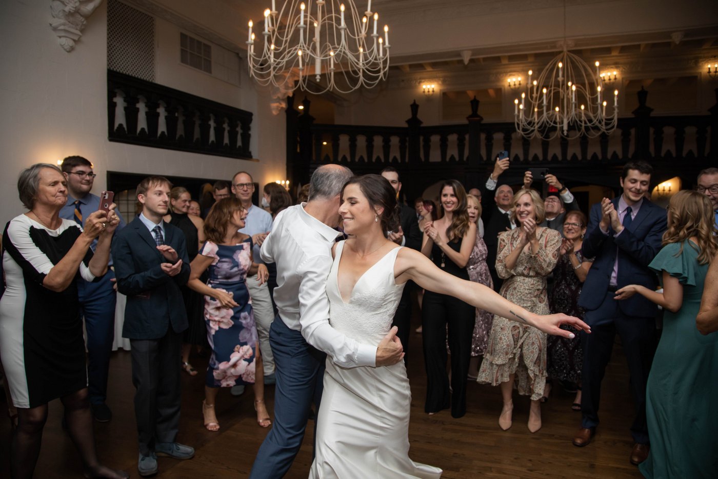 Bride dancing with her father as guests form a circle around them at fall wedding in Brookline