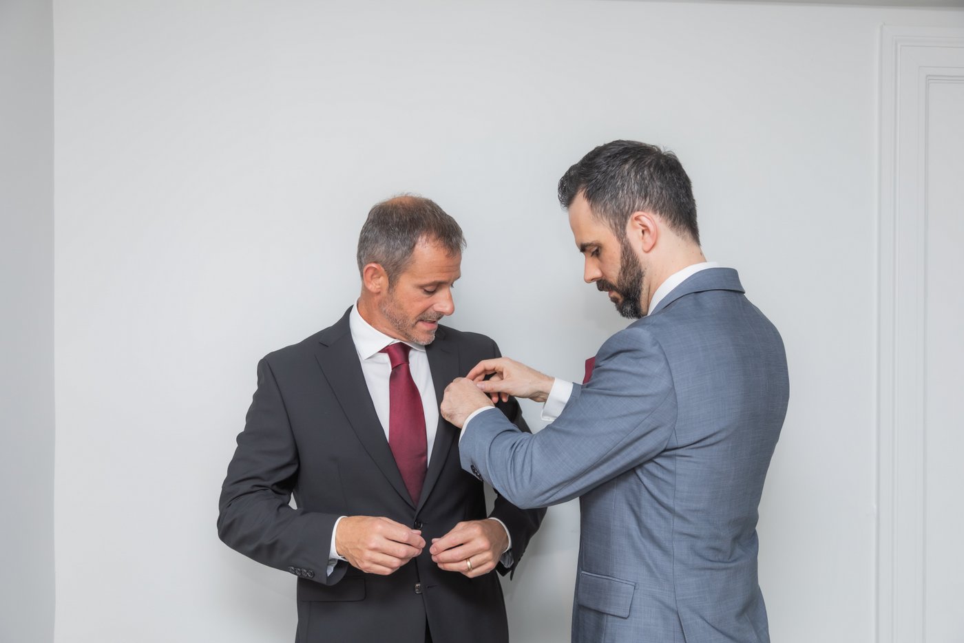 A groom adjusts his best man's handkerchief before the wedding