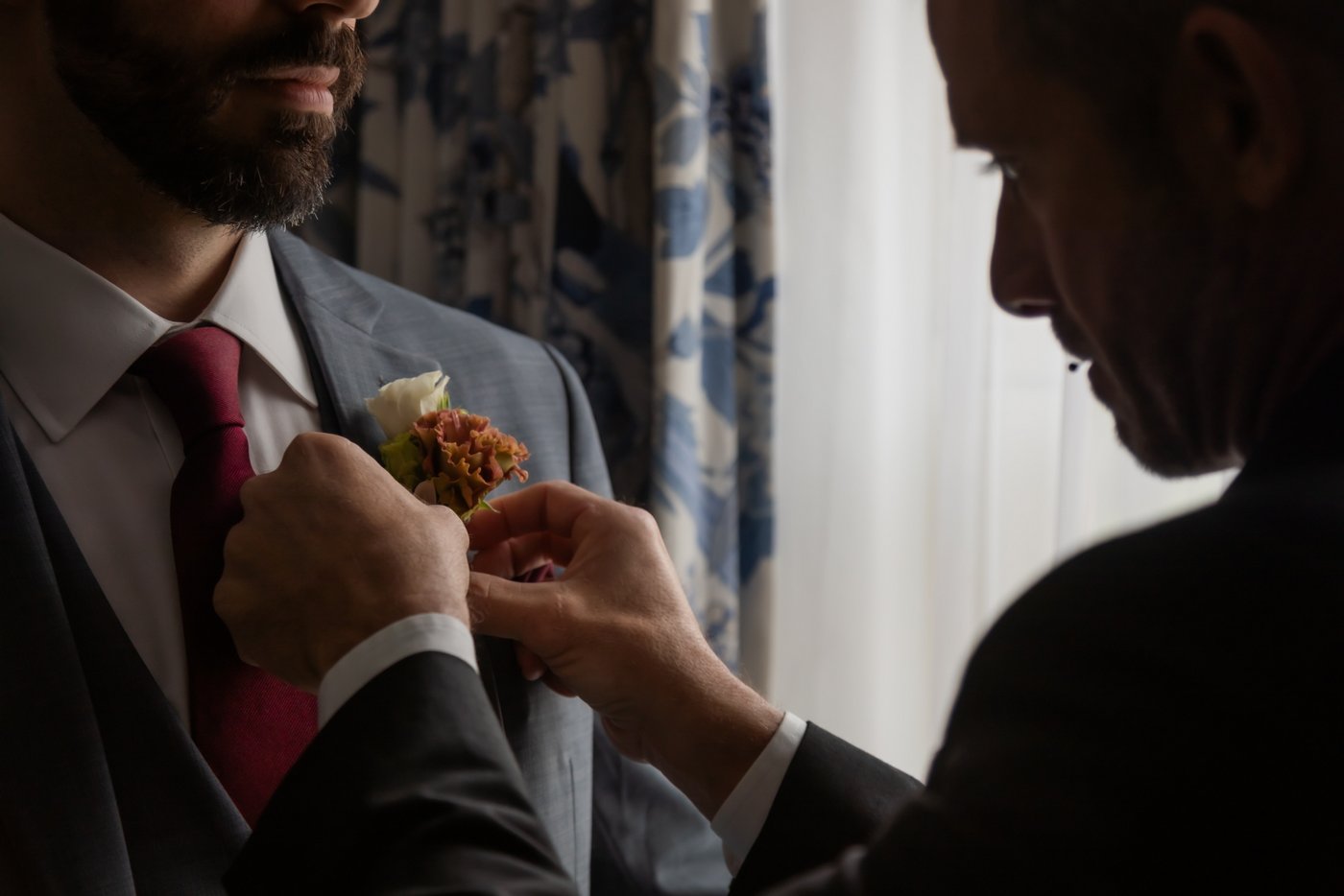 The best man pinning the groom's boutonniere