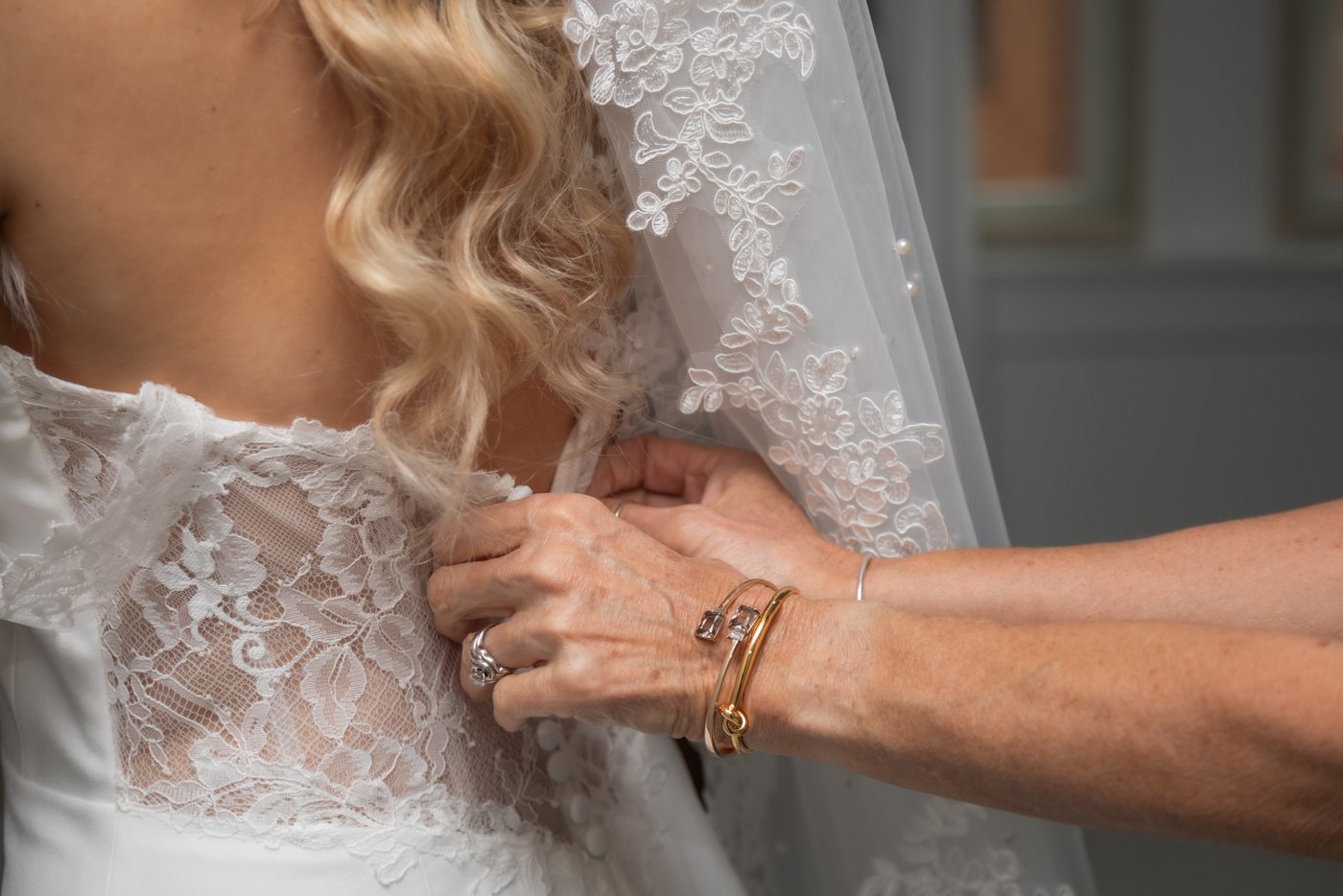 The bride's mother helps button the bride's dress