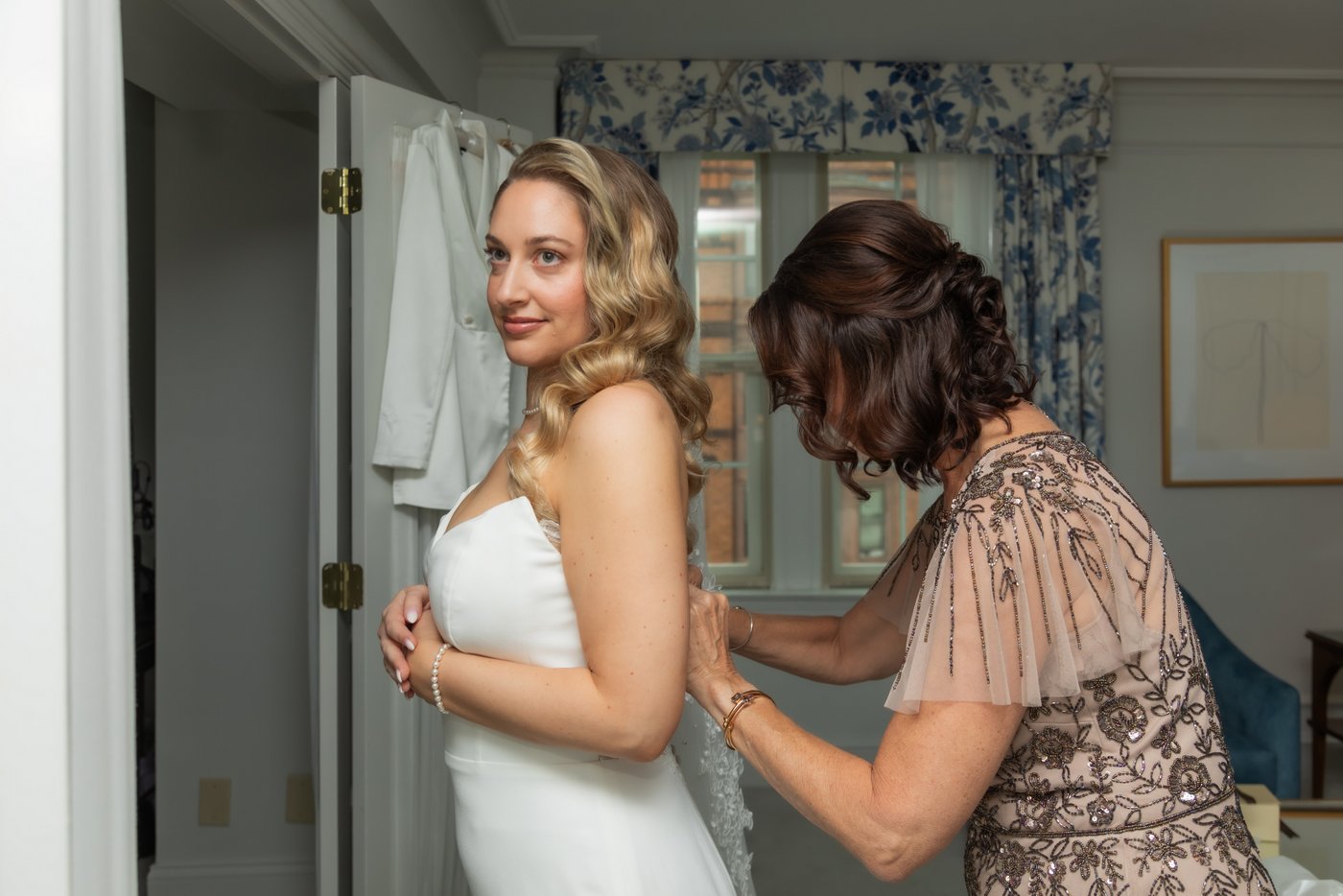 The bride's mother helps the bride get dressed