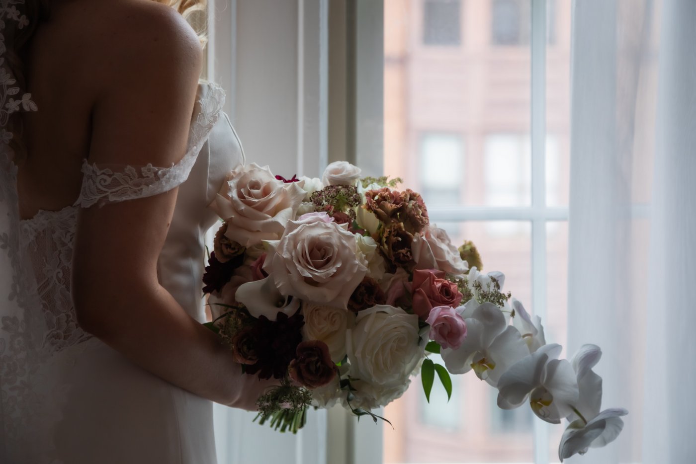 A close-up of the bride holding her large bouquet of flowers, photographed in a moody and romantic style by Boston wedding photographers Spagnolo Photography