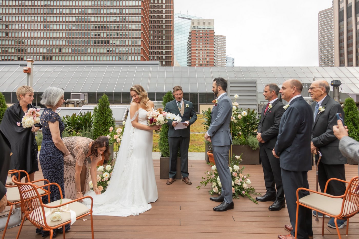 The mother of the bride adjusts the bride's train as she takes her place in front of the groom at their Terra Boston wedding