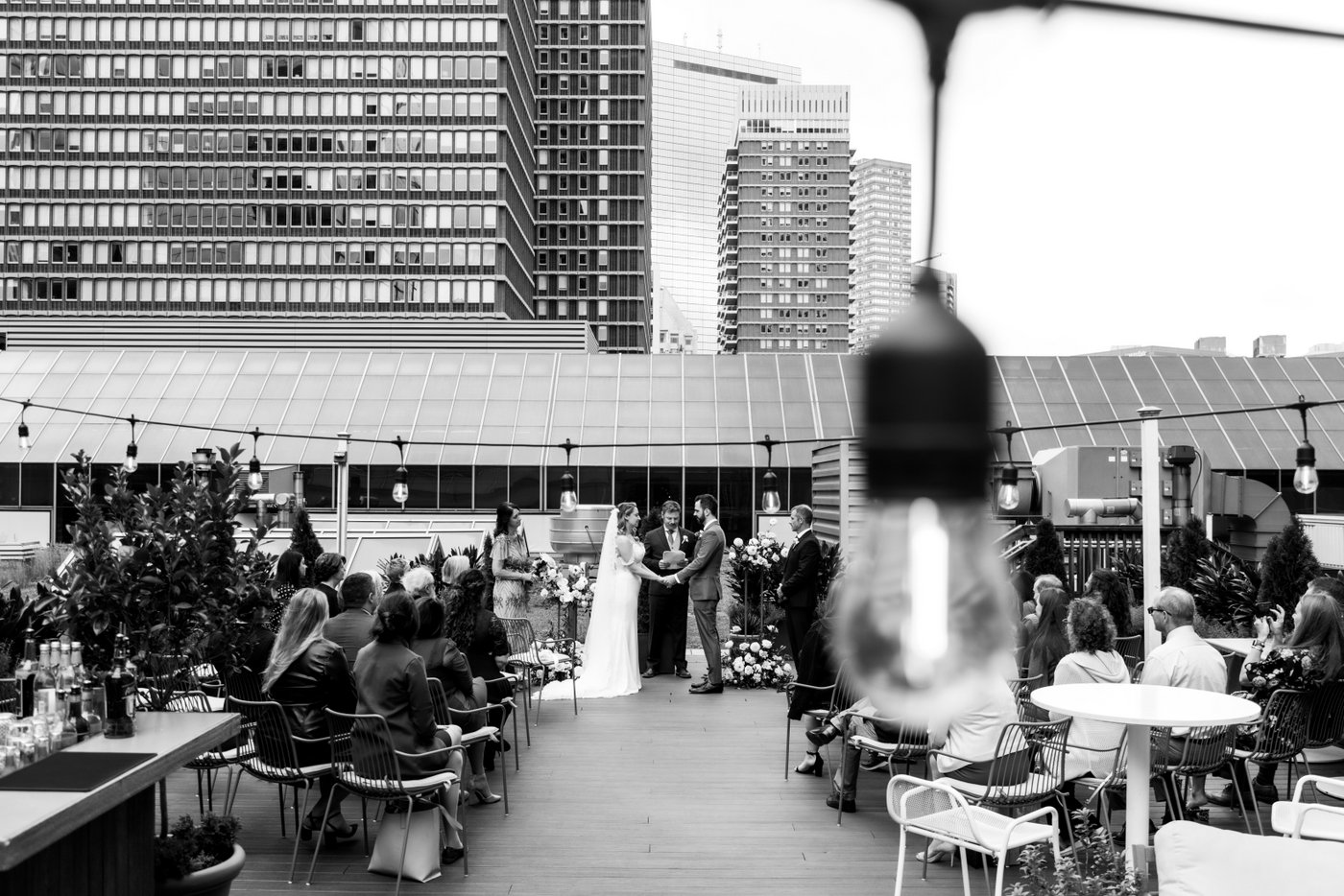 A creative black and white photo of the wedding ceremony on the rooftop of Terra at Eataly in Boston