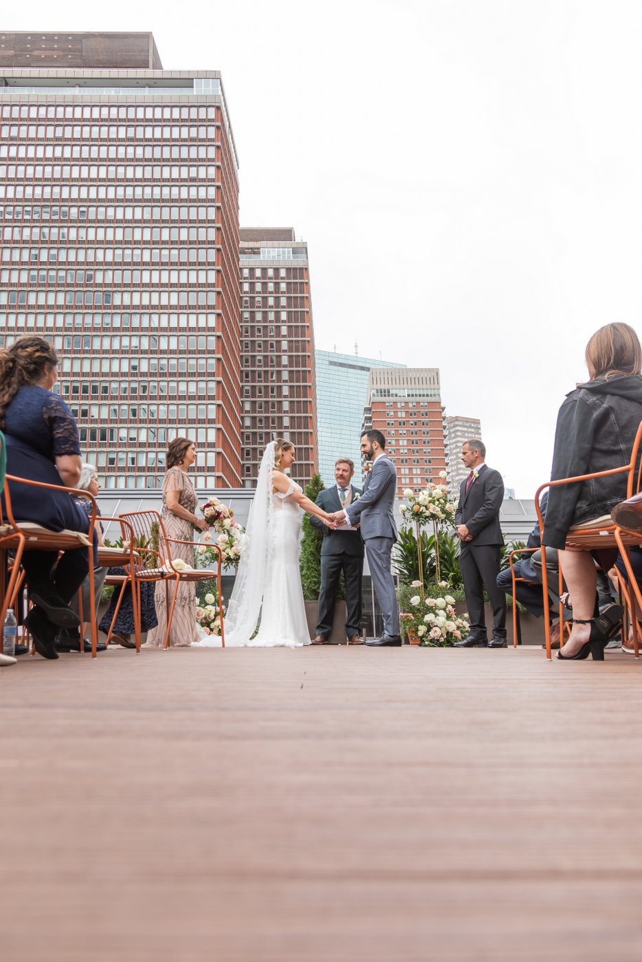 The bride and groom hold hands during their rooftop micro wedding ceremony at Terra at Eataly in Boston