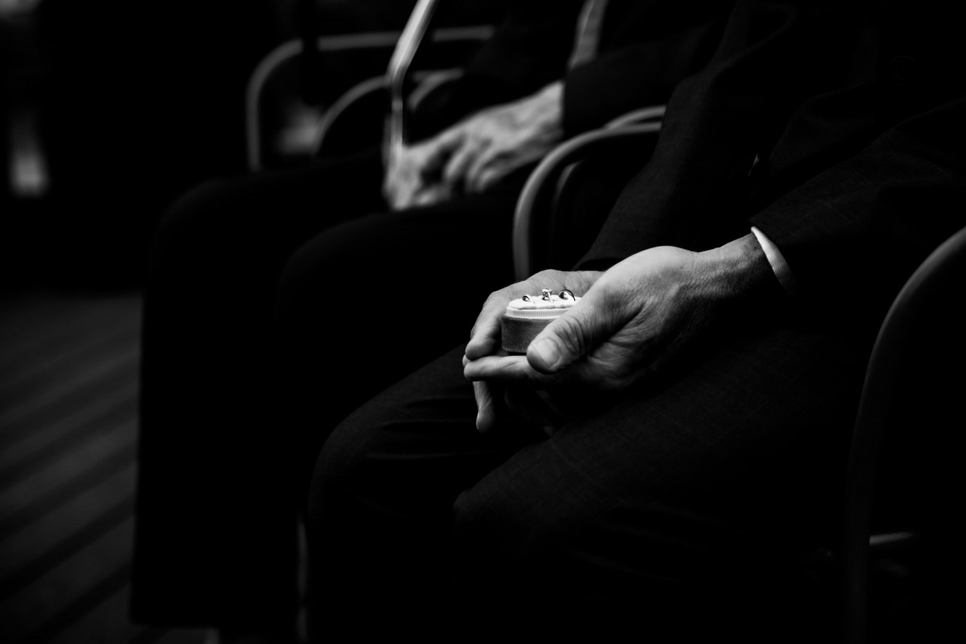 A black and white close-up photo of the best man's hands cupping the wedding bands during a rooftop wedding ceremony at Terr at Eataly in Boston