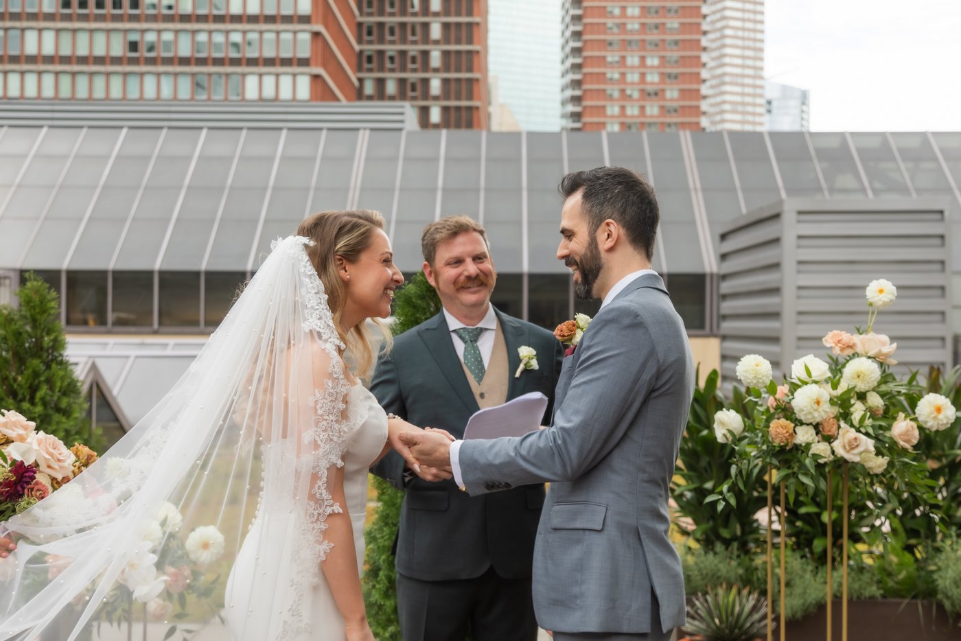 A bride and a groom laughing during their wedding ceremony on the rooftop of Terra at Eataly in Boston where they held their micro wedding, photographed by Boston wedding photographers Spagnolo Photography