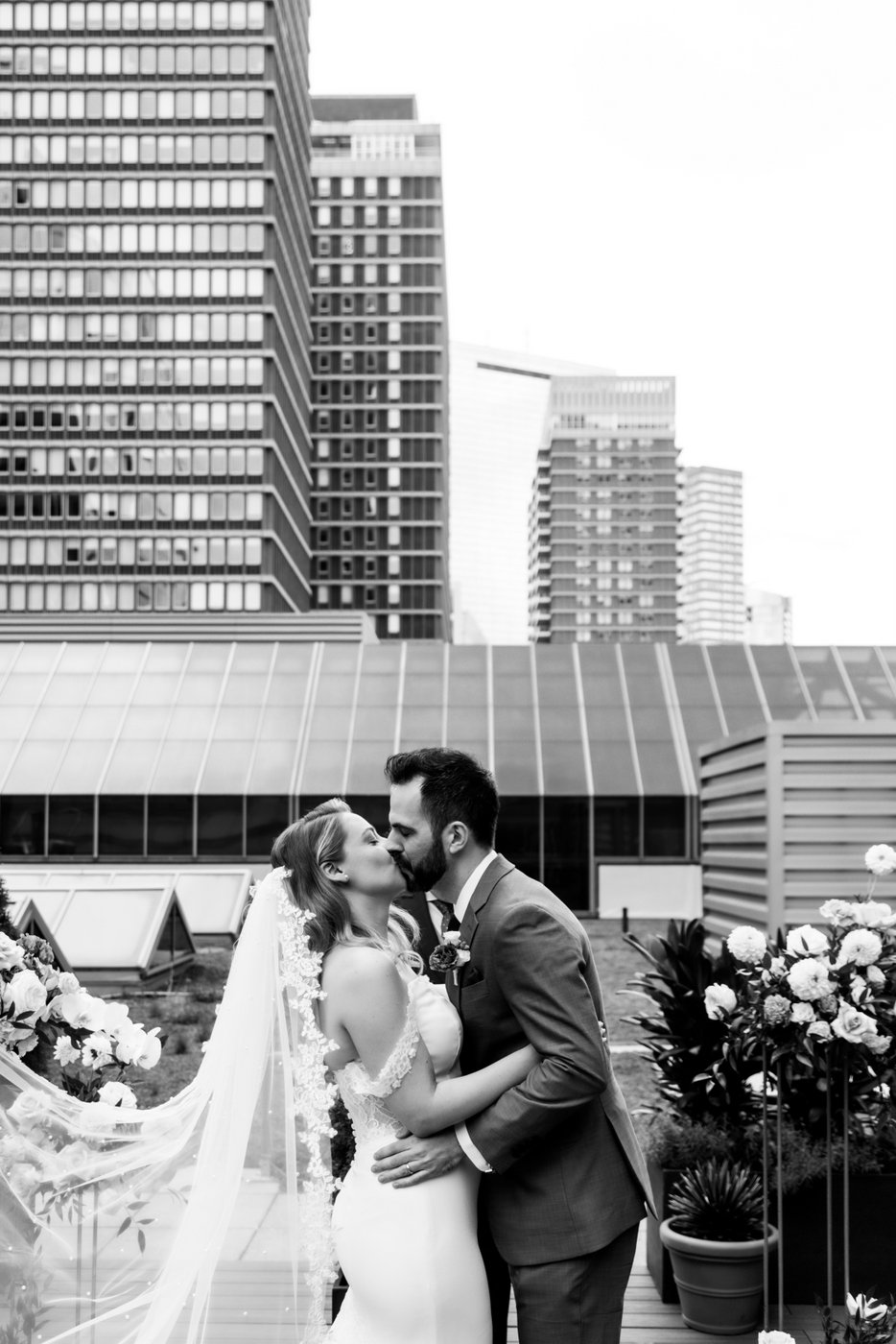 A black and white image of a bride and groom kiss on the rooftop of Terra at Eataly during their micro-wedding ceremony, photographed by Spagnolo Photography for their micro-wedding photography package.