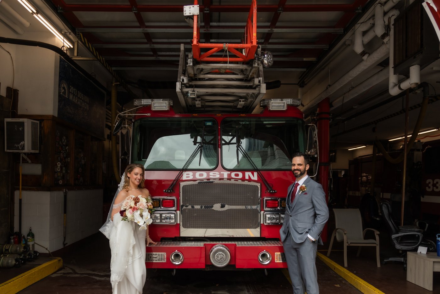 A bride and a groom posing in front of a fire truck at a fire station in Boston's Back Bay