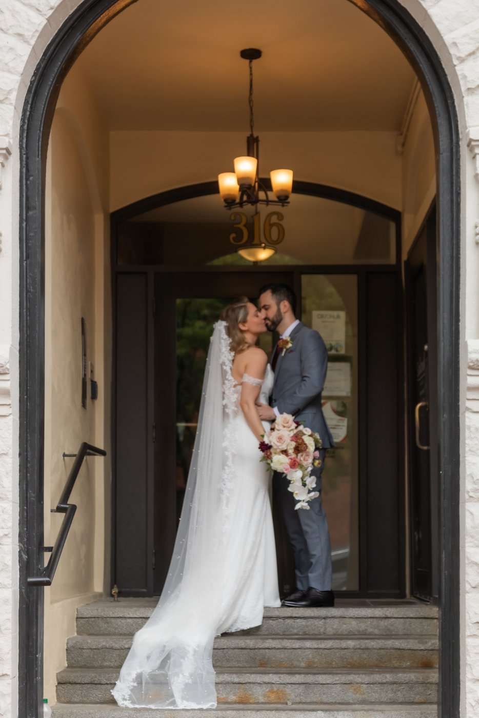 A bride and a groom kissing in the entryway of a building in Boston's Back Bay
