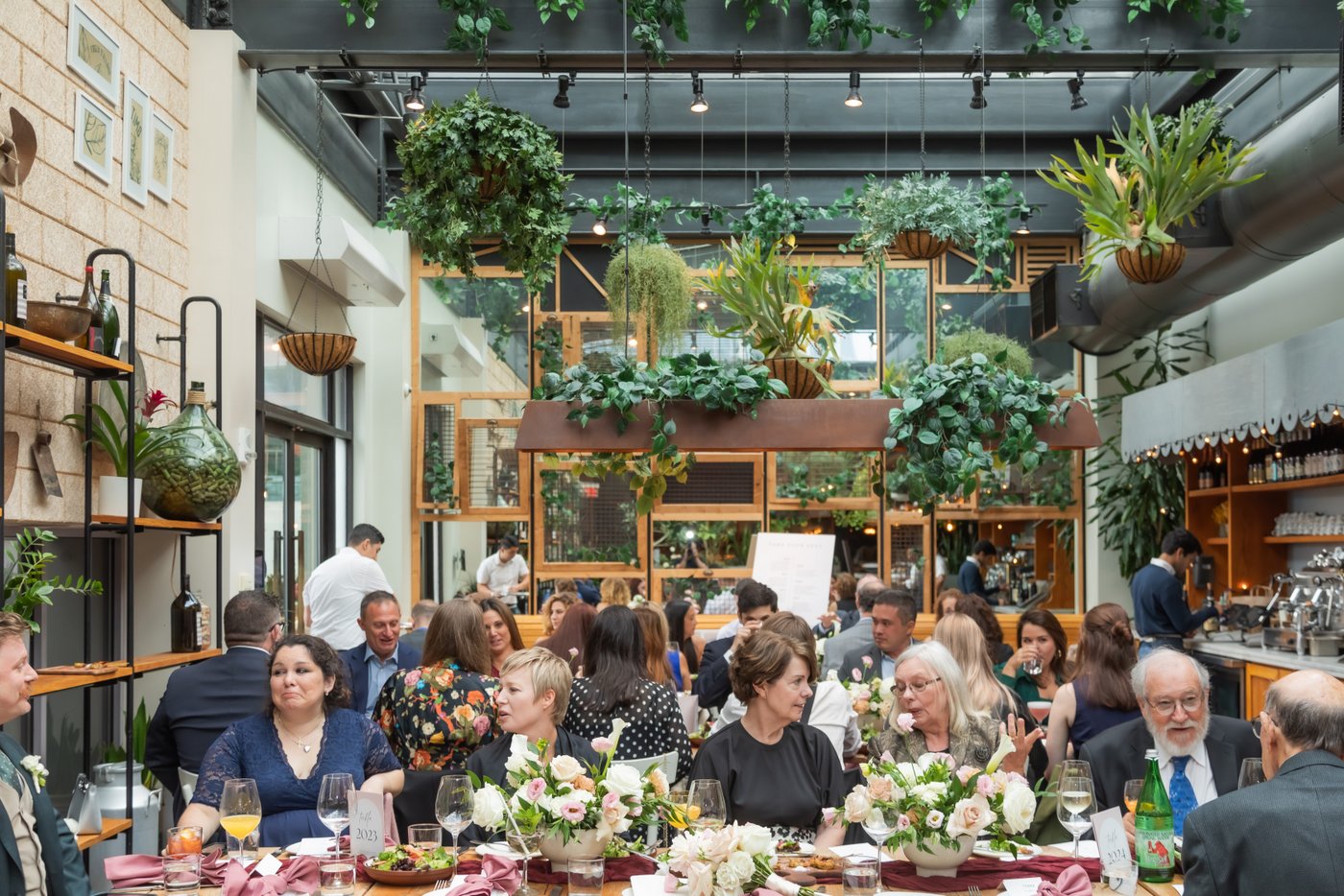 Guests are seated at long tables under hanging plants at Terra at Eataly