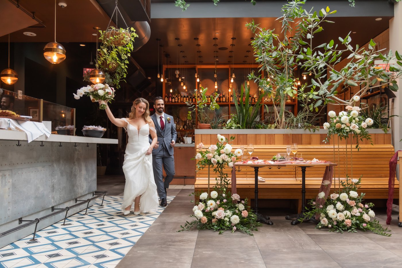 The bride raises her bouquet as she enters the wedding reception at Terra at Eataly in Boston