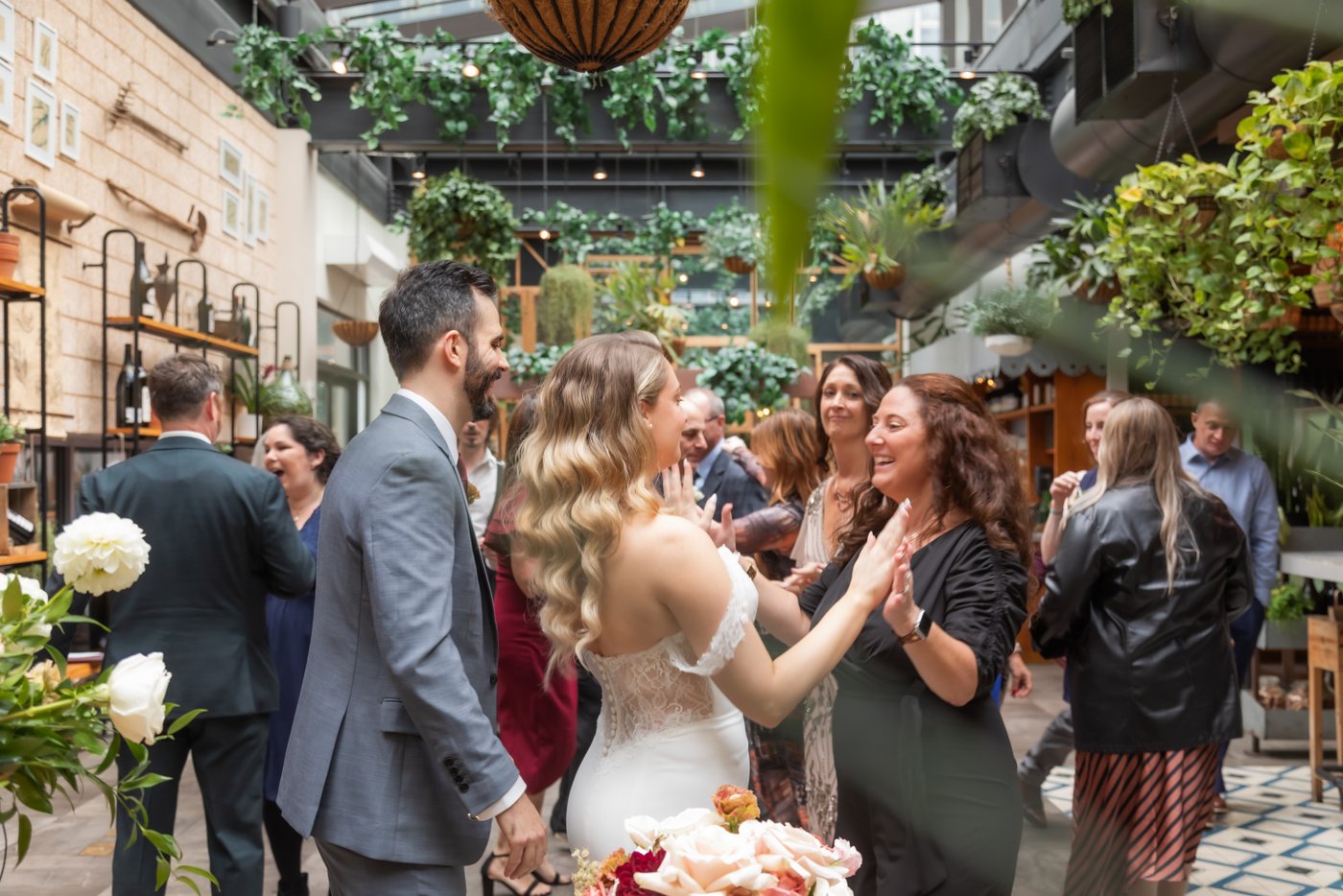 The bride and groom are surrounded by guests who are congratulating them at their wedding at Terra at Eataly in Boston