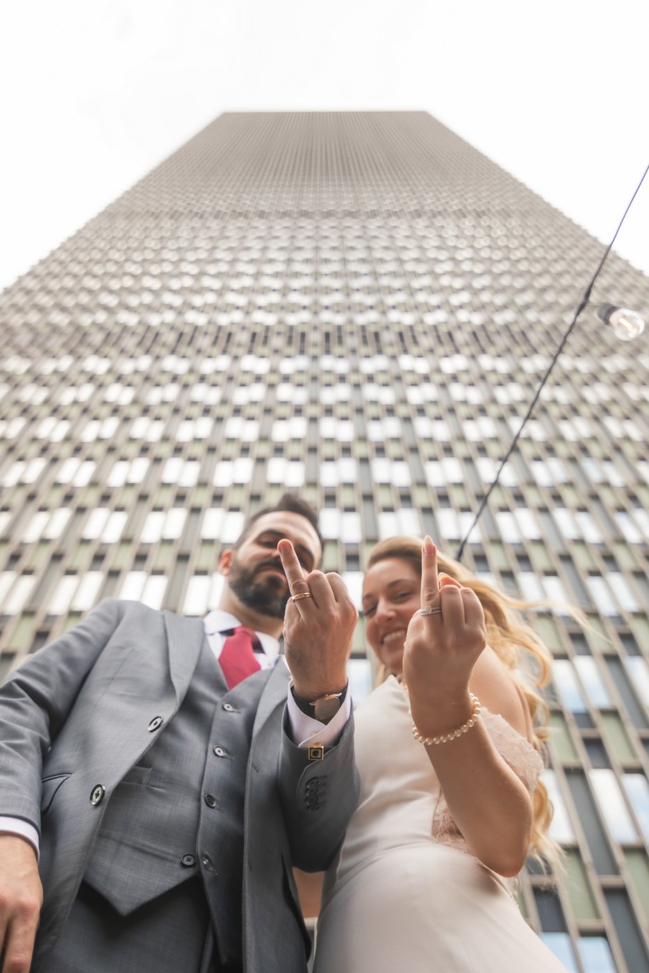 A bride and a groom show off their wedding rings in front of The Prudential Center Building during their wedding at Terra at Eataly in Boston.