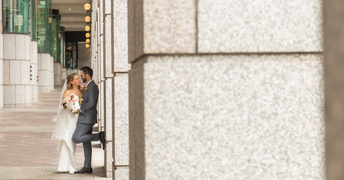 A bride and a groom gaze at each other by stone columns in Boston's Back Bay during their Terra Boston wedding at Eataly, photographed by Boston micro wedding photographers Spagnolo Photography in a natural, candid style.