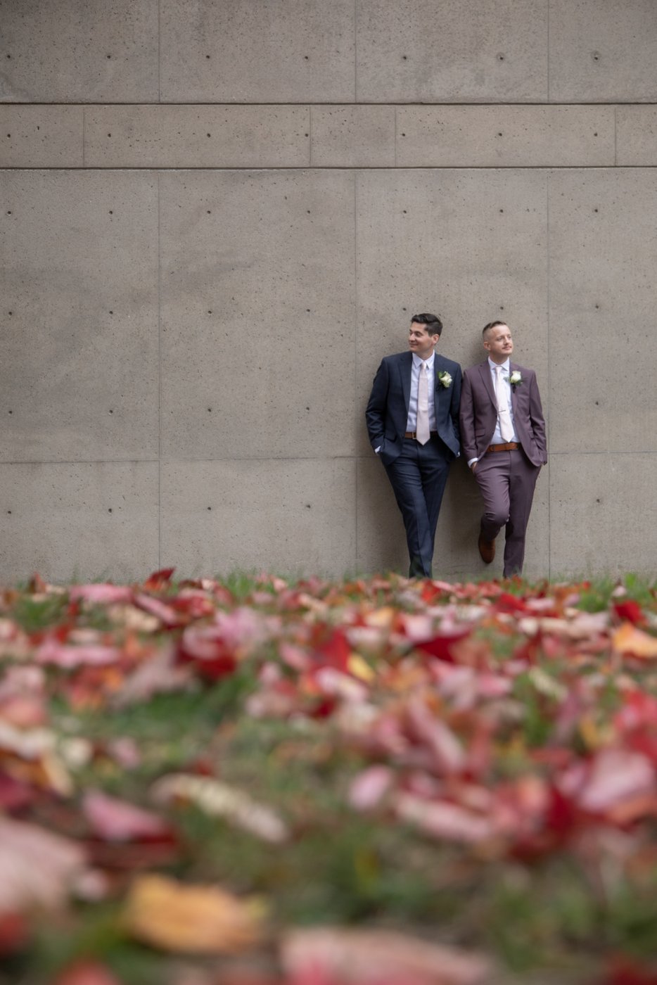 A portrait of two grooms leaning against a stone wall following their Cambridge City Hall wedding, with portraits around Cambridge, MA, by Spagnolo Photography.
