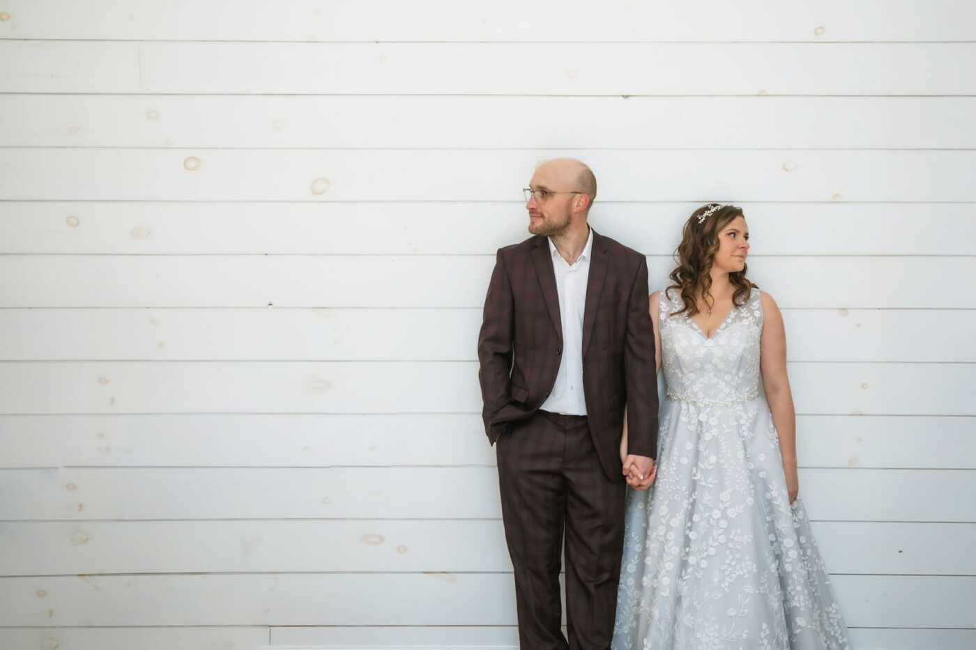 A bride and a groom hold hands and look in different directions during their Coonamessett wedding