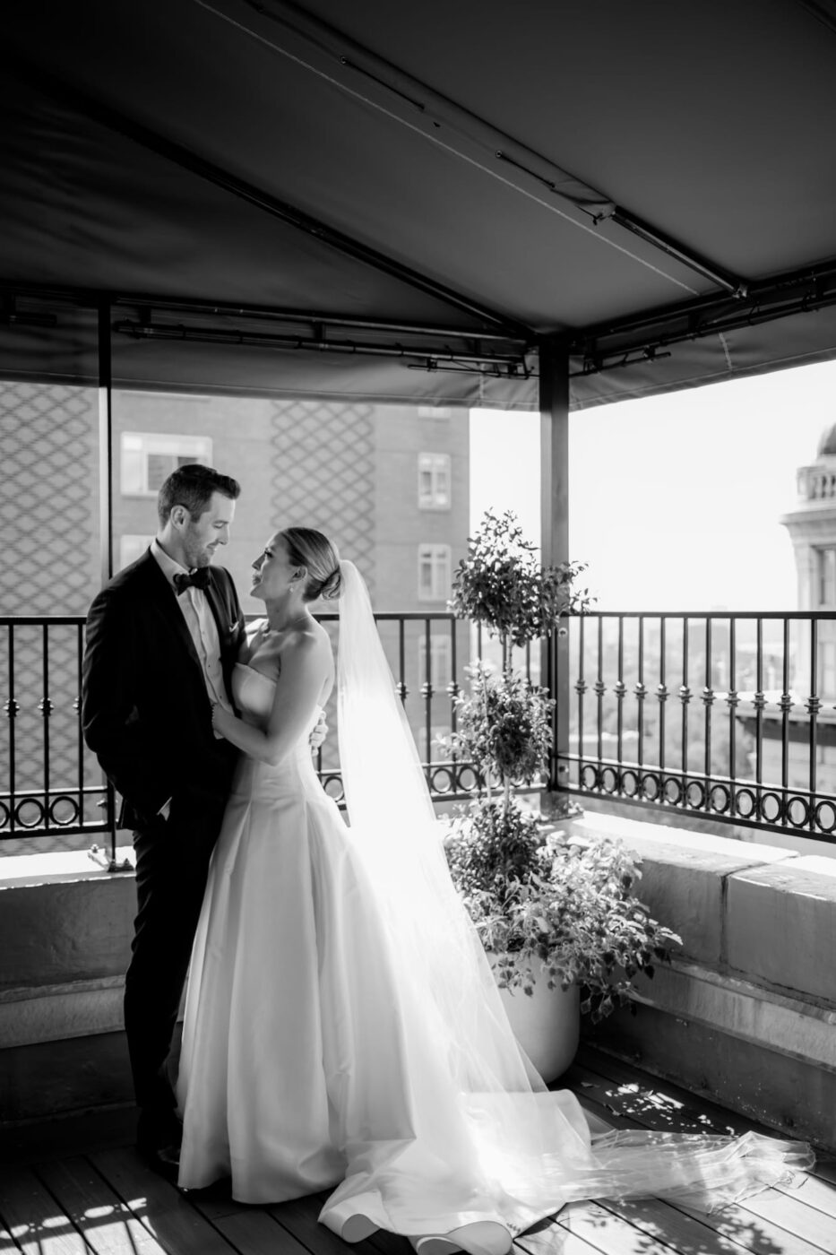 A black and white photo of a bride and a groom gazing at each other on the balcony of the Omni Parker House, following their First Look and vow exchange, photographed by Boston wedding photographers Spagnolo Photography