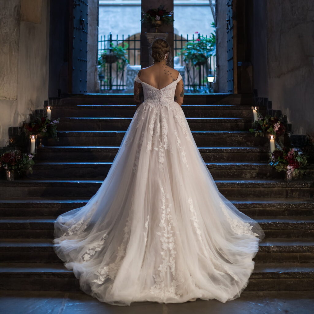 A dreamy portrait of a bride on the steps of the Great Hall at Hammond Castle, her train cascading down the stairs behind her