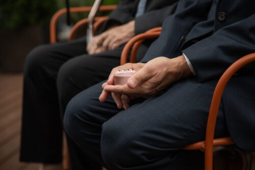 A close-up photo of the wedding bands in their velvet box that is resting in the palm of the best man during a micro-wedding at Terra Eataly - photographed by creative candid wedding photographers as part of their micro-wedding photography package